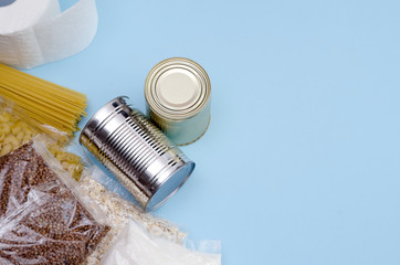 Food supplies food crisis quarantine period isolation on a blue background. Macaroni, buckwheat, oatmeal, canned food, sugar, toilet paper. Food Delivery, Donation, Coronavirus Quarantine. Copyspace.