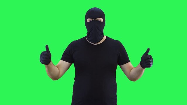 A man in a balaclava shows with two hands that everything is fine,green screen background