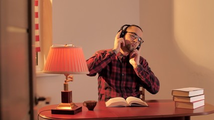 Student reads a book in the library and listens to music on headphones. Man enjoys music in quarantine due to coronavirus or covid-19. Self-isolation. Stay home and save your life