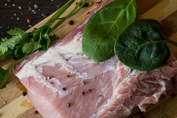 greens, seasonings and meat on a cutting board. a piece of pork, pepper, garlic, salt. Cook at...