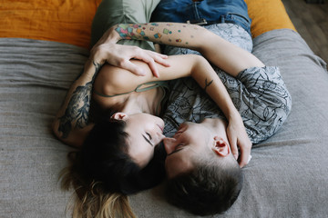 Young lovely couple lying in a bed. Man and woman embracing in bed. Young people deeply in love.  Kissing couple portrait. 