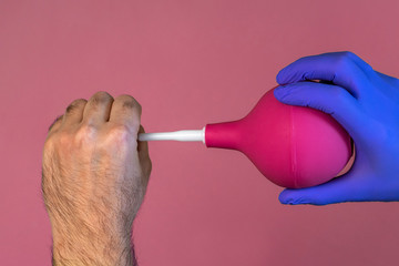 Demonstration of the use of enema. The doctor inserts an enema into his fist.