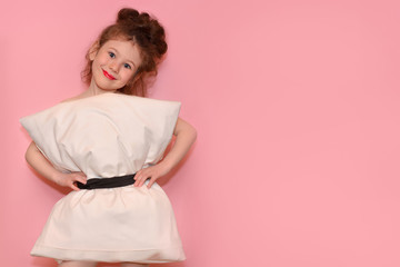 Beautiful little girl in a dress from pillows on a pink background. Crazy quarantine.Fashion 2020. Dress the pillow. Challenge 2020 due to home isolation.