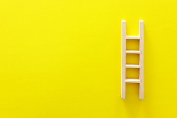 wooden ladder over yellow background