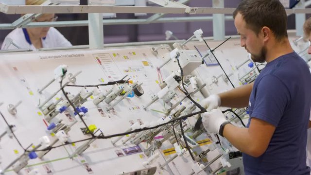 factory of cable products. women and men collect cable and connectors to cars