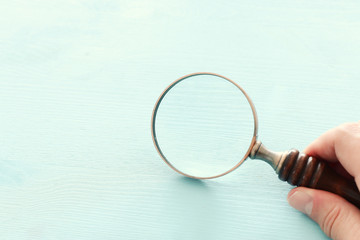 vintage magnifying glass with wooden handle over blue background.