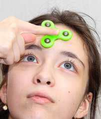 The girl twists the fidget spinner stress relief toy on her forehead.