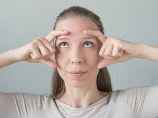 Gymnastics for the face. Woman does rejuvenating exercises for the face