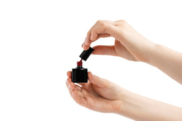 Beautiful red bottle of nail polish in hands. Isolated on white background.