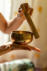 Close-up of of a young yogin woman holding a tibetan bowl and a stick in the beautiful and gentle...