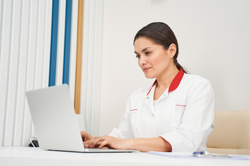 Concentrated brunette female person working at computer