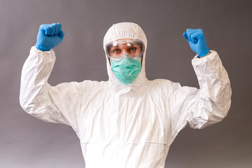 Male doctor with surgical mask, goggles and protective suit on gray backround.