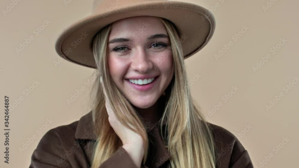 Sticker A close-up view of a gorgeous young woman wearing hat and coat is posing to the camera isolated over the beige background in studio