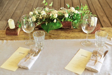 Wedding table in country style. The wedding festive table is decorated with floral arrangements, glasses, plates and cutlery, the table is covered with a beautiful tablecloth.