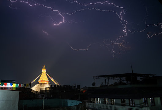 A thunderstorm front rages over the city of Kathmandu, in the place where Boudha Stupa is located. Lightning strikes and a stupa with night illumination are visible. - Powered by Adobe