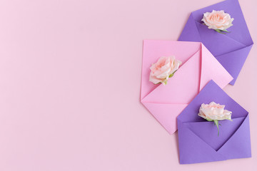 Purple and pink paper open envelopes with full small rose flowers on color background. Spring, summer concept. Romance, love notes, greeting card for March 8 International Woman's, Valentine's day