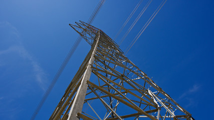 High voltage electrical tower. Electric poles in front of blue sky.