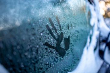 Handabdruck auf gefrorenem Autofenster