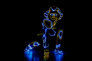 A man in the neon costume of Pharaoh is dancing in the dark