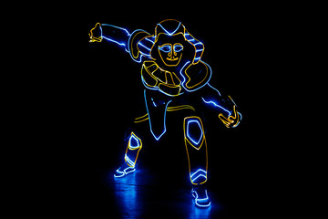 Obraz na płótnie Canvas A man in the neon costume of Pharaoh is dancing in the dark