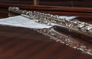 Flute lying on a sheet with notes, selective focus.