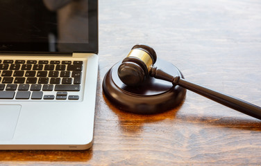 Judge gavel and a laptop, wooden background. Online auction concept - obrazy, fototapety, plakaty