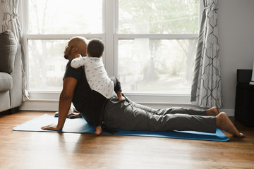 Father and son working out at home with baby during quarantine