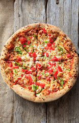 Fast food concept. Pizza with crunchy dough and fresh vegetables on wooden surface.