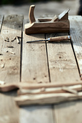 wooden background. On the village table lie dotches, sawdust, and on the background of the bit and jointer plane. vertical picture. Wood thread tool. solar lighting