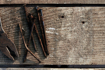 Rusty pliers and bent old nails lie on a tree desktop. rust. cracked, scratched homemade table. construction background