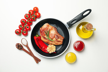 Pan with fried steaks and ingredients for cooking on white background, top view