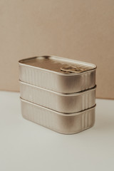 Vertically stacked tower consisting of three steel tin cans. Blank canned goods on neutral pastel background.
