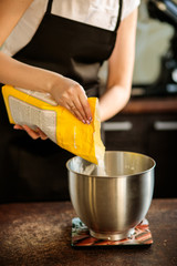 Fototapeta na wymiar A pastry chef pours flour into a mixer bowl 