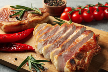 Board with fried steaks on gray background. Grilled food