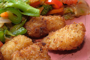 Fried chicken nuggets and salad on plate .