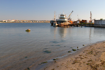 Beach and seashore with a pier and fishing boats in the background. Sea resort town in the...