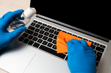 Coronavirus prevention concept. Cleaning and disinfecting a laptop with disinfectant spray and...