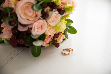 Wedding rings and a bouquet on a white surface, there is space to insert text
