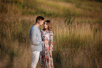 young couple resting in nature in a field. couple at sunset