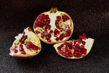 Juicy pomegranate on a black shiny background. Bright pomegranate berries.