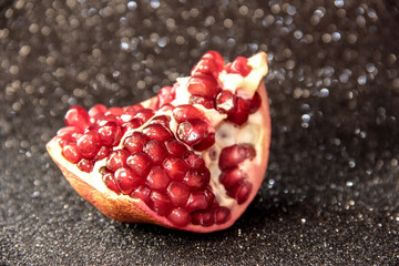 Juicy pomegranate on a black shiny background. Bright pomegranate berries.