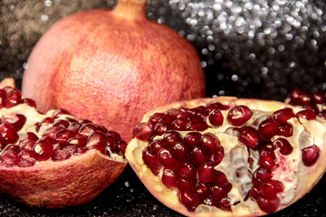 Juicy pomegranate on a black shiny background. Bright pomegranate berries.