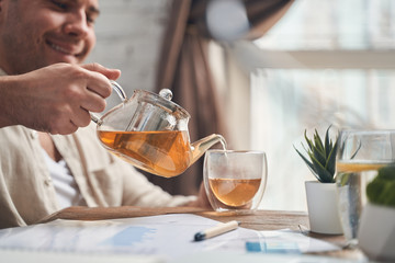 Man filling a mug with a herbal drink