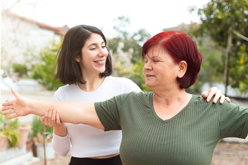 the mature woman and her young daughter do yoga in the garden. The mother and daughter, who are in quarantine for the coronavirus, are spending time at home.