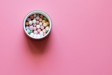 Box of decorative cosmetics on pink background. Powder in balls.