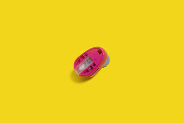 plastic pink hole puncher standing on the yellow background. concept of office chancery. free space for text