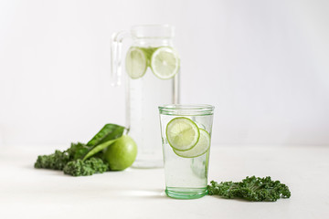 Warm clear water with slices of lime and cale around on the light background 
