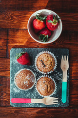 Appetizing Chocolate Muffins made with wholemeal flour and brown sugar with strawberries for a healthy breakfast.