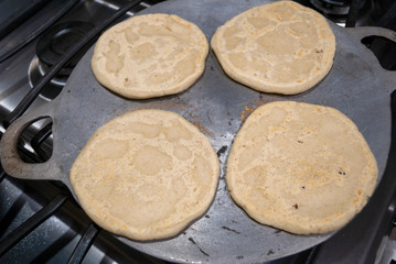 Nutritious handmade corn tortilla cooked on a metal griddle on a gas stove in a Guatemalan home.