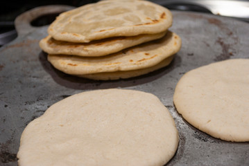 Nutritious handmade corn tortilla cooked on a metal griddle on a gas stove in a Guatemalan home.